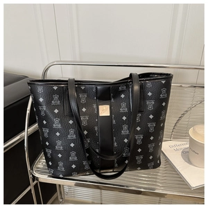 Detailed view of black tote bag with bear print and golden metal logo plate