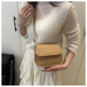 Nahaufnahme der kamelfarbenen Satteltasche mit Prägung und goldenem Fashion-Logo