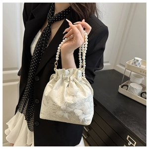 Detail der weißen Spitzen-Beuteltasche mit 3D-Schmetterlingen und elegantem Perlengriff