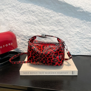 Glossy leopard print red tote bag with silver hardware and detachable strap on books
