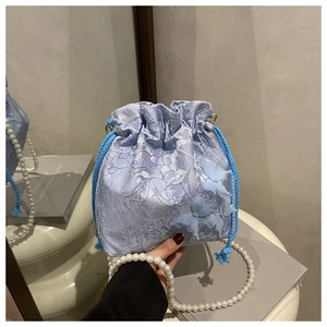 Detail der hellblauen Beuteltasche mit Blumen-Jacquard-Struktur und 3D-Schmetterling