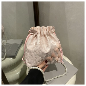 Nahaufnahme der rosa Spitzen-Beuteltasche mit 3D-Schmetterlingen und Perlenkette