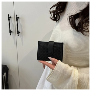 Close-up of black woven leather card holder with snap button held by a hand