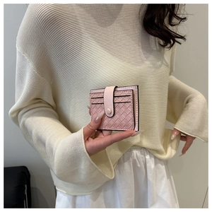 Pink woven leather card holder with snap closure held by model in casual sweater