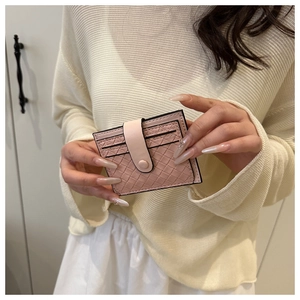 Detail of pink woven leather card holder with snap button closure held by a model