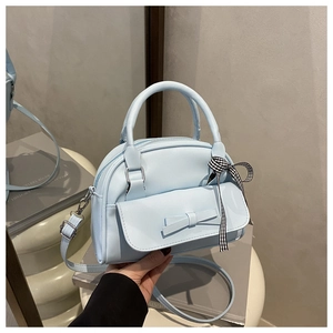 Detail of light blue square crossbody bag with bow decoration and checkered ribbon accent