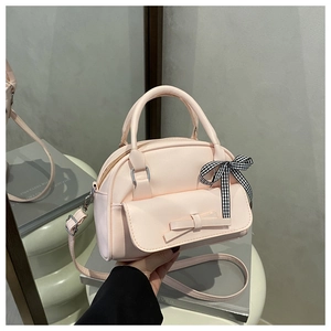 Detail of light pink shell bag featuring a matte texture and decorative fabric bow