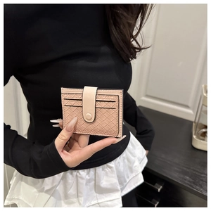 Détail d'un porte-cartes en cuir tressé rose avec texture croisée et bouton-pression