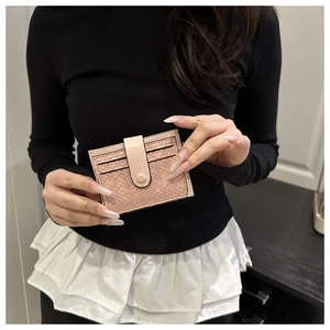 Close-up of a pink woven texture card holder with snap closure held by a model