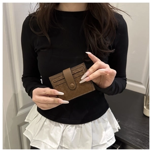 Close-up of brown woven leather card holder with snap closure held by hand