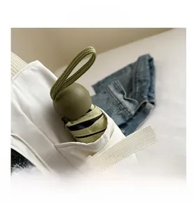 Gros plan d'un parapluie pliant vert olive rangé dans la poche d'un sac en toile