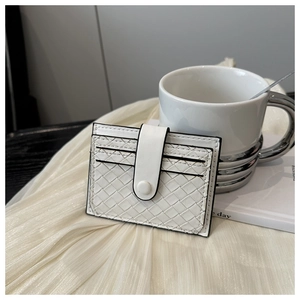 Detailed view of a white woven leather card holder with secure snap button closure
