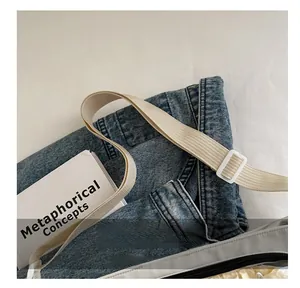 Détail du sac gris clair montrant la bandoulière réglable et la boucle en plastique