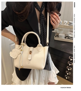 Detail of off-white lychee grain leather tote bag with top handle and puppy charm