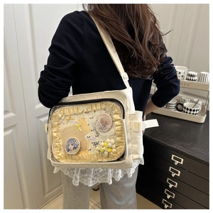 Détail du sac ita blanc montrant la fenêtre PVC avec badges anime et nœud chic