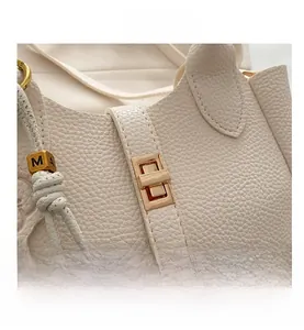 Macro shot of ivory pebble leather texture with gold metal clasp and M-A cube charm
