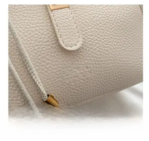Macro detail of white lychee grain leather handbag with gold metal hardware and logo