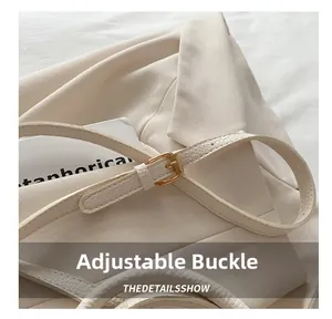 Detail of adjustable golden metal buckle on beige lychee texture shoulder bag strap