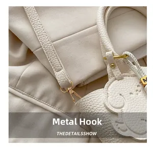 Detail of white lychee leather texture with gold metal hook and puppy bag charm