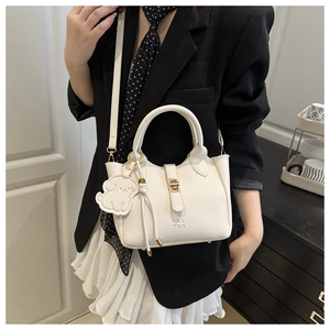 White lychee leather bucket bag with gold clasp and cute dog charm worn over black blazer