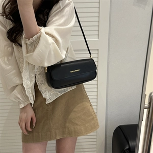 Minimalist black matte leather baguette bag with gold lettering and slim shoulder strap