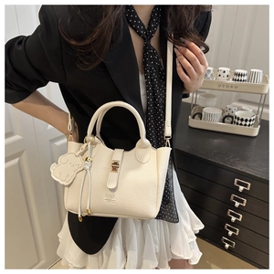 Detail of cream white pebbled leather tote with gold hardware and dog charm