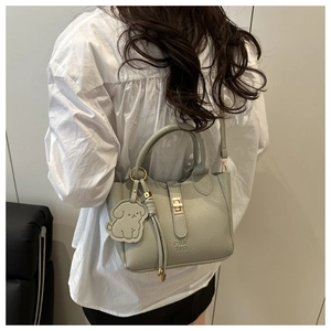 Detailed back view of a light sage green pebbled leather tote bag with a cute puppy charm