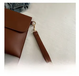 Detailed close-up of the caramel brown faux leather strap and golden metal hook on bag
