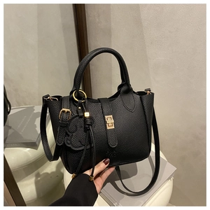 Detail of black pebbled leather tote bag with gold rotary clasp and cloud pendant