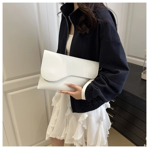 Close-up of a white envelope bag with an asymmetrical wave-cut flap and silver hardware