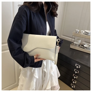 Detail of creamy white envelope clutch featuring an asymmetrical wave flap and wrist strap