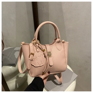 Detail of pink lychee leather tote bag with golden lock and cute bear charm accessory