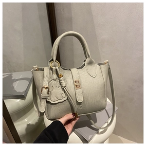 Detail of light grey lychee leather tote bag with gold lock and elephant charm