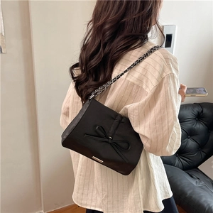 Women's black chain bag with bow detail and glossy finish in a chic crossbody style