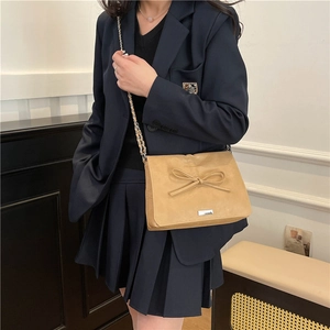 Light brown crossbody bag with decorative bow and metal chain strap in high-quality leather
