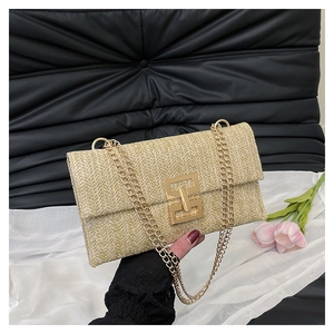 Détail d'un sac enveloppe tissé beige avec texture à chevrons et fermoir géométrique doré