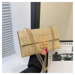 Vue détaillée du sac enveloppe en paille tressée beige avec fermoir décoratif doré en H