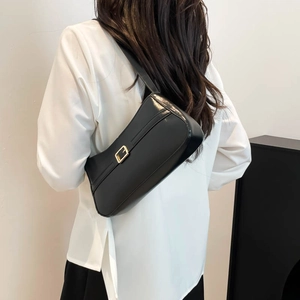 Minimalist black matte leather underarm bag with gold buckle shown on a female model
