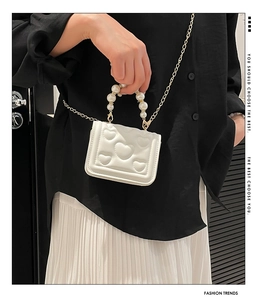 Detail of white PU leather mini bag with heart embossing and faux pearl handle