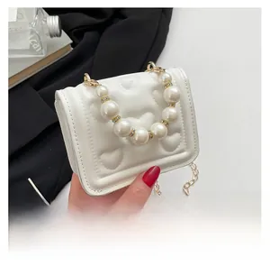 Detailed view of heart-quilted white mini bag with elegant pearl handle and gold chain