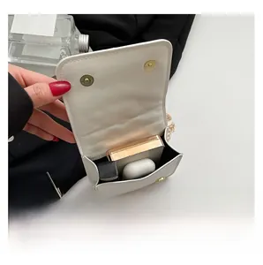 Internal capacity of the white mini chain bag showing storage for lipstick and earphones