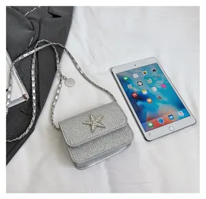 Detailed size comparison of a silver glitter crossbody bag with star decor next to a tablet