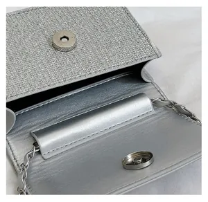 Macro shot of silver sequined crossbody bag with metallic magnetic snap and chain strap