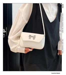 White faux leather crossbody bag featuring a silver metal butterfly detail shown on model
