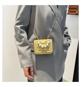 Detail of yellow quilted mini bag with heart textures and pearl handle on a blazer