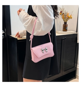 Detail of pink rectangular shoulder bag with a decorative silver metal butterfly bow