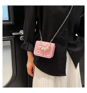 Close-up of pink mini crossbody bag featuring heart embossed pattern and pearl handle