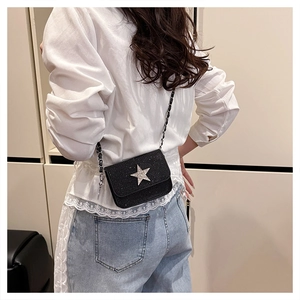 Dettaglio mini borsa nera con paillettes, stella scintillante e tracolla a catena in metallo