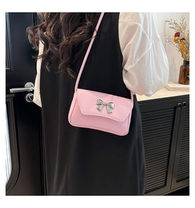 Detailed close-up of a pink baguette bag featuring a silver metallic bow and PU leather texture