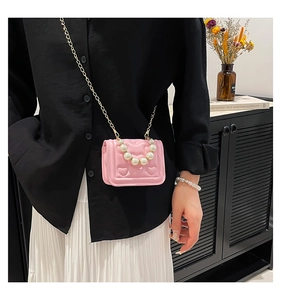 Pink heart quilted mini bag with pearl handle and gold chain strap shown on model